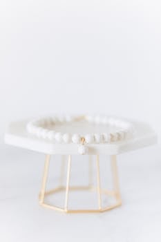 Minimalist white bead bracelet displayed on a geometric stand, ideal for jewelry design and fashion concepts.
